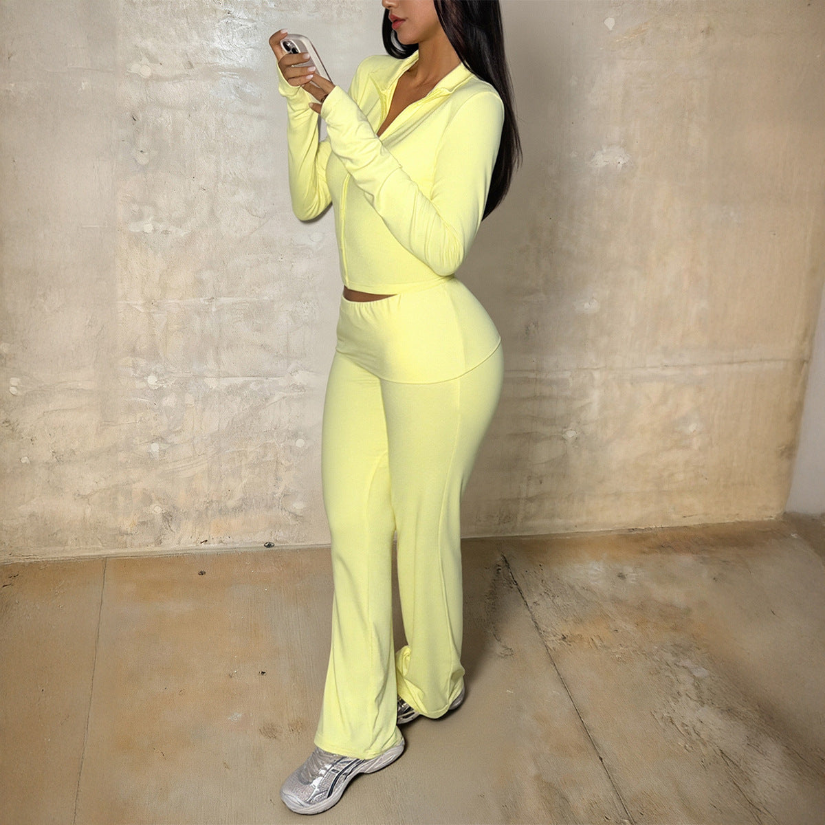 Woman wearing yellow yoga sports jacket and tight-fitting pants two-piece set standing indoors